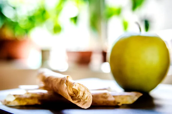 Apple pastille wrapped in straws lies on a table on the background of an apple.