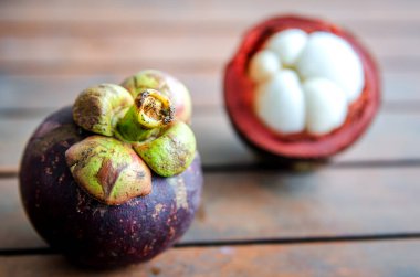 Olgun bütün mangosten kesilmiş meyve ahşap bir masa üzerinde bir arka plan üzerinde.