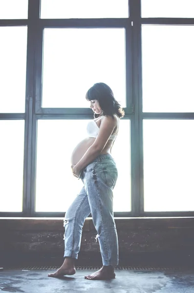 Beautiful Pregnant Girl Jeans Background Huge Window Hugging Her Tummy — Stock Photo, Image