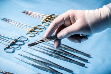 Cerrah ameliyathanede tıbbi aletleri arka plan üzerinde elinde neşter.