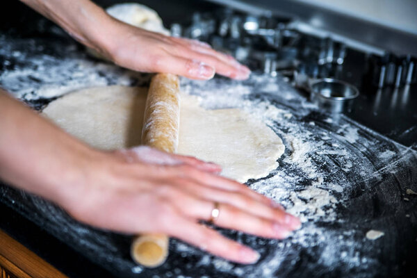 Rolling dough using a wooden rolling pin.