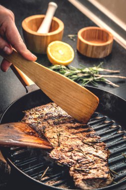 Aşçı lezzetli sulu biftek biftek ızgara tavada kavurma, döner.