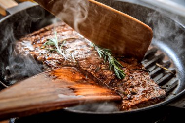 Cook sığır eti biftek ızgara tavada kızartma.