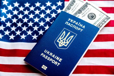 Yüz dolarlık banknotlarla Amerikan bayrağının arka planında Ukrayna biyometrik pasaportu.