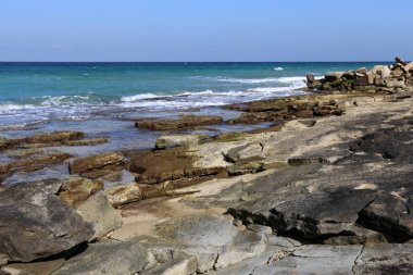 Akdeniz kıyısında açık bir parkta taş yalan 