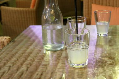 deniz kıyısında bir restoranda masada soğuk su ve alkolsüz içecek ile bir bardak var 