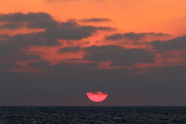 Kuzey İsrail'de Akdeniz'de ufukta güneş batıyor ve gece çöküyor. 