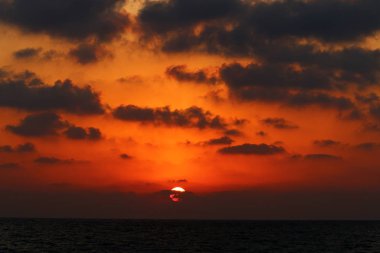 Kuzey İsrail'de Akdeniz'de ufukta güneş batıyor, gündüz bitiyor ve gece çöküyor 