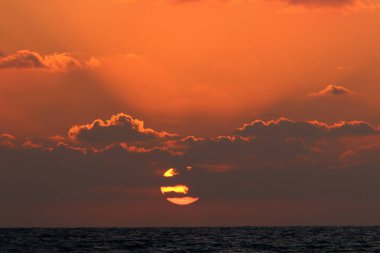 Kuzey İsrail'de Akdeniz'de ufukta güneş batıyor, gündüz bitiyor ve gece çöküyor 