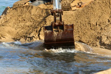 Büyük bir ekskavatör Akdeniz kıyısında İsrail'de bir şantiyede çalışır 