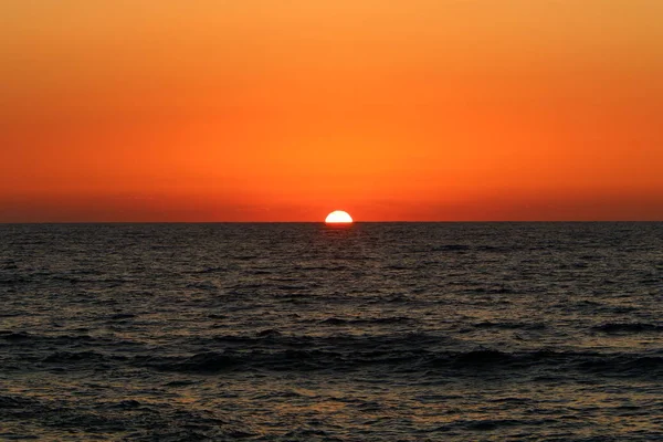 The sun sets over the horizon on the shores of the Mediterranean Sea in the north of Israel and night falls
