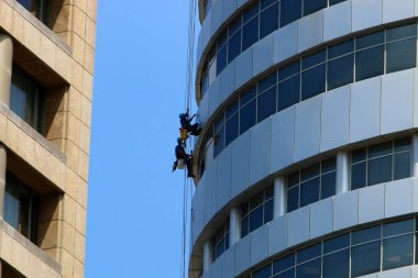 İşçiler İsrail 'in büyük bir şehrindeki yüksek bir binanın camlarını silerler. 