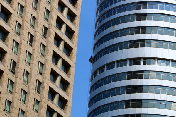 workers wash windows in a tall building in a big city in Israel