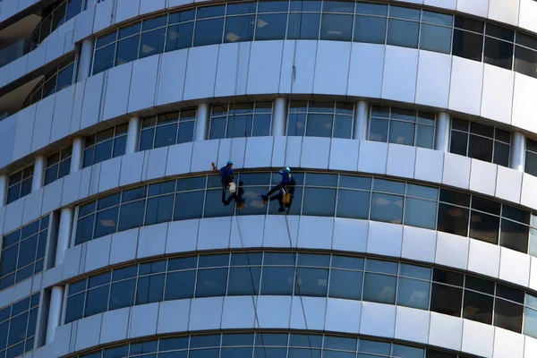 workers wash windows in a tall building in a big city in Israel