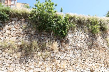 Taş ve betondan yapılmış yüksek duvar. Taş duvar dokusu 