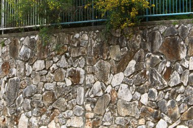 Taş ve betondan yapılmış yüksek duvar. Taş duvar dokusu 