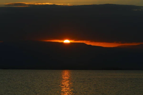 The sun rises from behind the mountains in Jordan and illuminates the Dead Sea. Hot summer in Israel