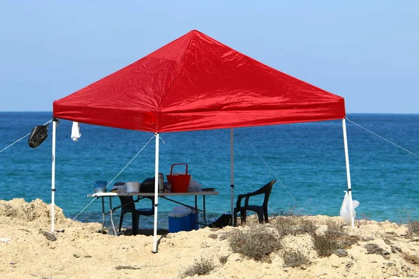 a tent stands on a beach on the shores of the Mediterranean Sea in northern Israel