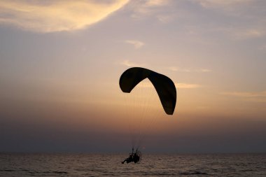 Bir adam Akdeniz 'in üzerinde bir kanatla uçuyor. İsrail 'de sıcak yaz 