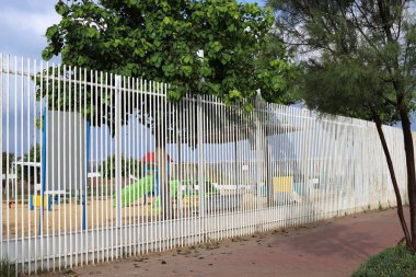 Ağaçlar ve çiçekler İsrail 'de bir şehir parkında çit boyunca yetişir. 
