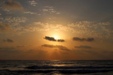 Kırmızı bulutlu gökyüzünün arka planında kızıl-sıcak güneş 