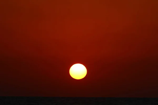赤い曇り空を背景にした赤熱い太陽 — ストック写真