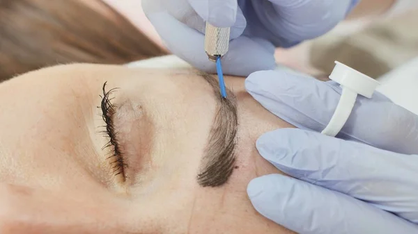 Permanent makeup. Permanent tattooing of eyebrows. Cosmetologist applying permanent make up on eyebrows- eyebrow tattoo.