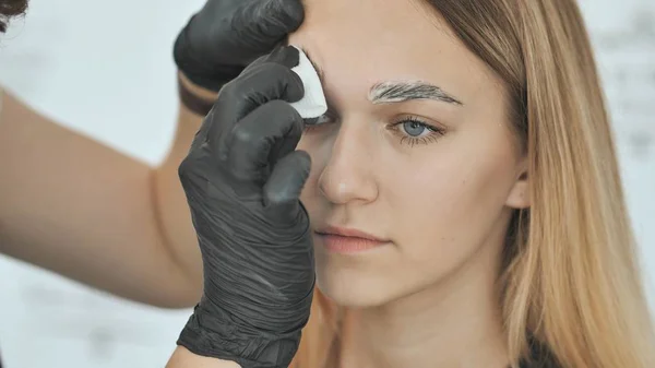 Removing bleach cream with a cotton swab. Create permanent eyebrow makeup.
