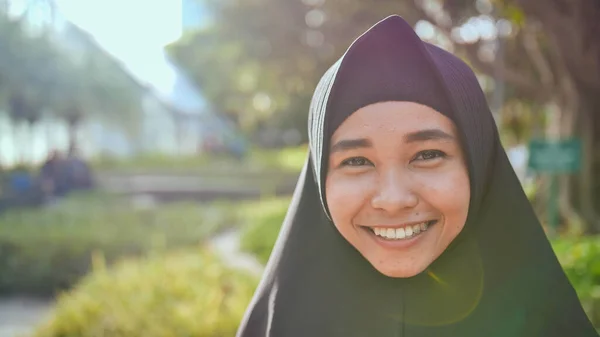 Portrait of a young smiling Muslim girl in a black hijab.