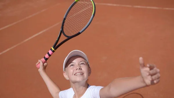 A young tennis player serves in a tennis game.
