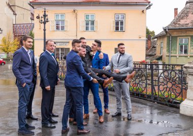 Sibiu, Romanya, 07 Ekim 2017: Damadın arkadaş küçük kare kilisede önünde tut. Sibiu şehir Romanya