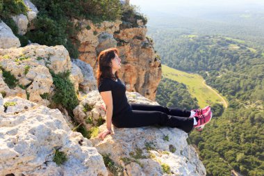 cliff üzerinde oturan ve mesafe içine seyir siyah bir eşofman kadında