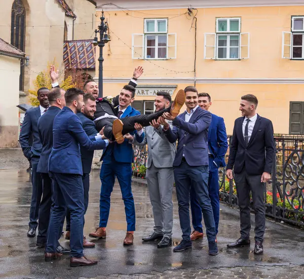 Sibiu, Romanya, 07 Ekim 2017: Damadın arkadaş küçük kare kilisede önünde tut. Sibiu şehir Romanya