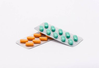 İki tam kapalı paket - biri turuncu dikdörtgen hapları ile ve diğeri dikdörtgen şeklinde yeşil hapları yalan beyaz bir arka plan üzerine