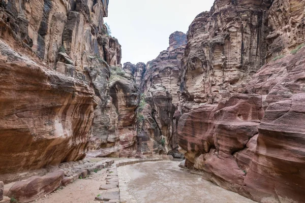 Al-Siq - desfiladeiro que atravessa as muralhas de rocha vermelha até Petra - a capital do reino Nabateano na cidade de Wadi Musa, na Jordânia — Fotografia de Stock