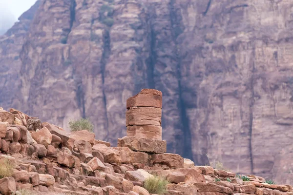 Fragment of the column remaining from the time of the Roman Empire against the background of the red rock in Petra. Near Wadi Musa city in Jordan