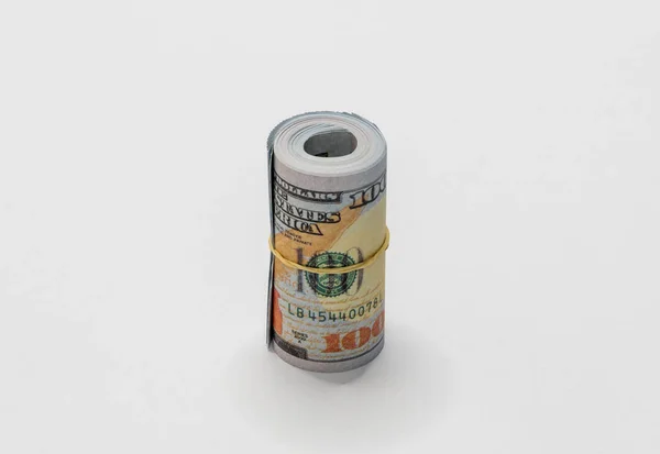 Un tas de dollars américains en coupures de billets de 100 dollars enroulés et maintenus ensemble avec un simple élastique isolé sur un fond blanc . — Photo