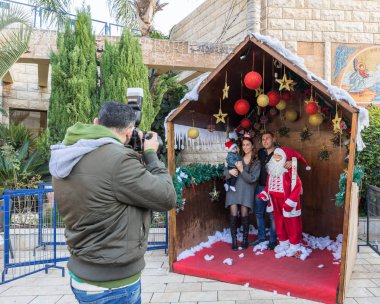 Nazareth, İsrail, 20 Aralık 2018: Bir fotoğrafçı Noel Baba şehirde Nazareth, İsrail ile genç bir aile fotoğrafı alır