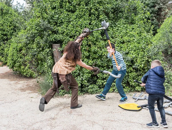 Een bezoeker vecht met een festival deelnemer gekleed als een barbaar met plastic wapens op het Purim festival met koning Arthur in de stad Jeruzalem, Israël — Stockfoto