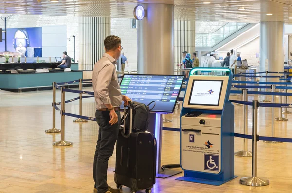 Туристические проверки информации возле электронного информационного стенда для проверки рейсов в лобби международного аэропорта Бен-Гурион, недалеко от Тель-Авива в Израиле — стоковое фото