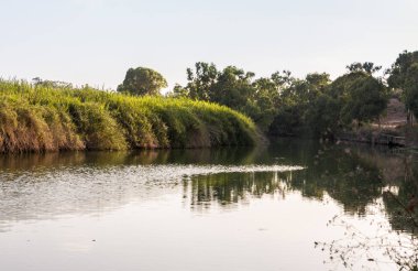 Kuzey İsrail'de Kfar Vitkin yakınlarındaki Alexander Nehri üzerinde batan güneşin ışınlarıpanoramik görünümü