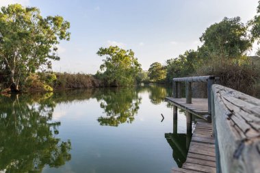 Kuzey İsrail'de Kfar Vitkin yerleşim yakınında, Alexander nehri kıyısında ahşap bir iskele kalıntıları üzerinde batan güneşin panoramik görünümü
