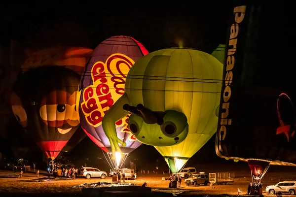 Napompowane i oświetlone balony na gorące powietrze są na ziemi i uczestniczyć w nocnym show na gorącym powietrzu balon festiwalu — Zdjęcie stockowe