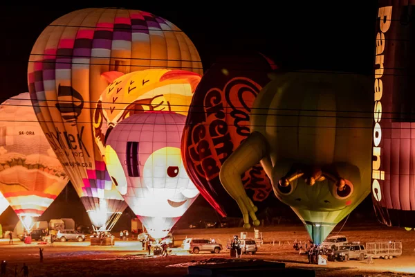 Napompowane i oświetlone balony na gorące powietrze są na ziemi i uczestniczyć w nocnym show na gorącym powietrzu balon festiwalu — Zdjęcie stockowe