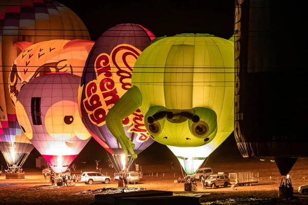 Napompowane i oświetlone balony na gorące powietrze są na ziemi i uczestniczyć w nocnym show na gorącym powietrzu balon festiwalu — Zdjęcie stockowe