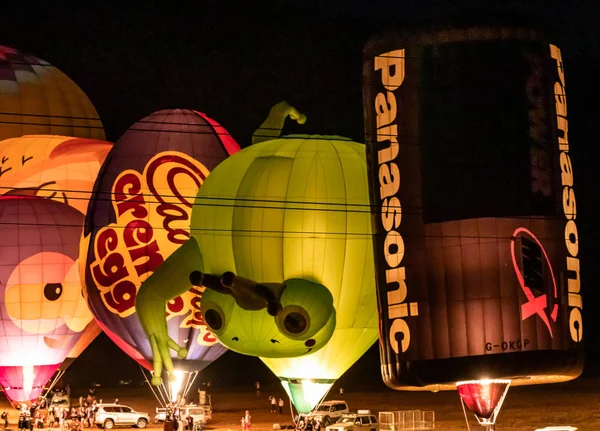 Napompowane i oświetlone balony na gorące powietrze są na ziemi i uczestniczyć w nocnym show na gorącym powietrzu balon festiwalu — Zdjęcie stockowe