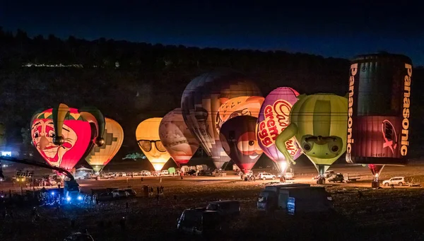 Napompowane i oświetlone balony na gorące powietrze są na ziemi i uczestniczyć w nocnym show na gorącym powietrzu balon festiwalu — Zdjęcie stockowe