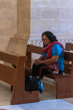 Mümin bir bankta oturur ve İsrail'de Nasıra yakınlarındaki Tavor Dağı'nda bulunan Katolik Hıristiyan Transfiguration Kilisesi'nin merkez salonunda dua eder.