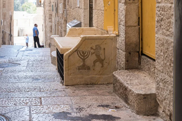 Bank met een afbeelding van een menora en een leeuw in een rustige straat van de oude stad in Jeruzalem, Israël — Stockfoto