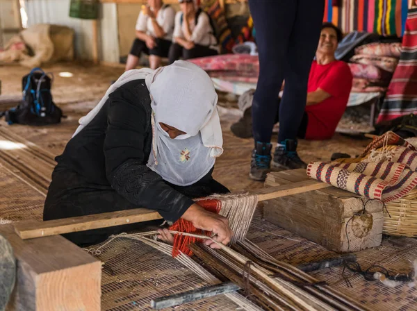 A Bedouin woman shows how to make the right fabric on a simple loom in a Bedouin village near the Mitzpe Ramon city — 스톡 사진